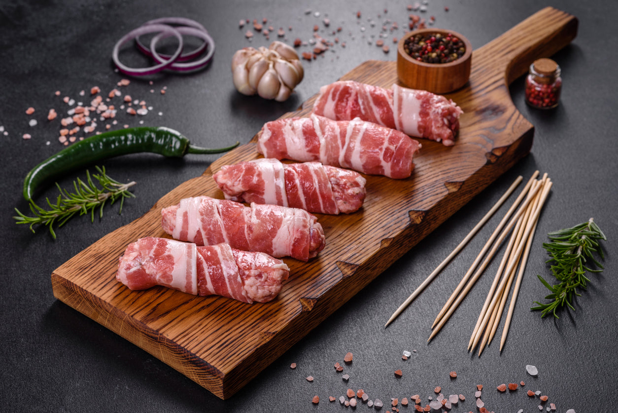 Rustic smoked and cured heritage pork bacon sliced on a wooden board with crispy cooked strips, herbs, and a farmhouse breakfast setting.